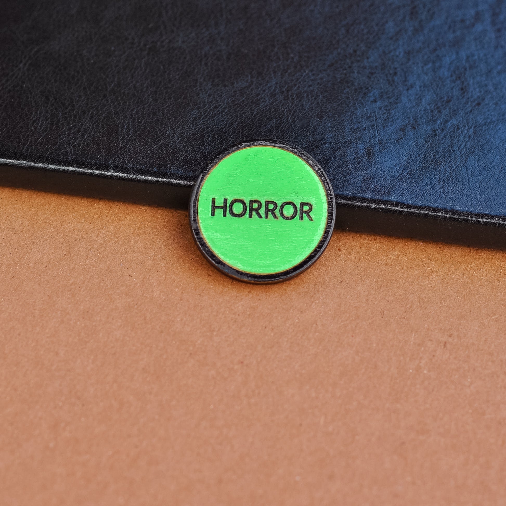 Green retro vhs label horror pinback style button that reads 'Horror' on a textured surface