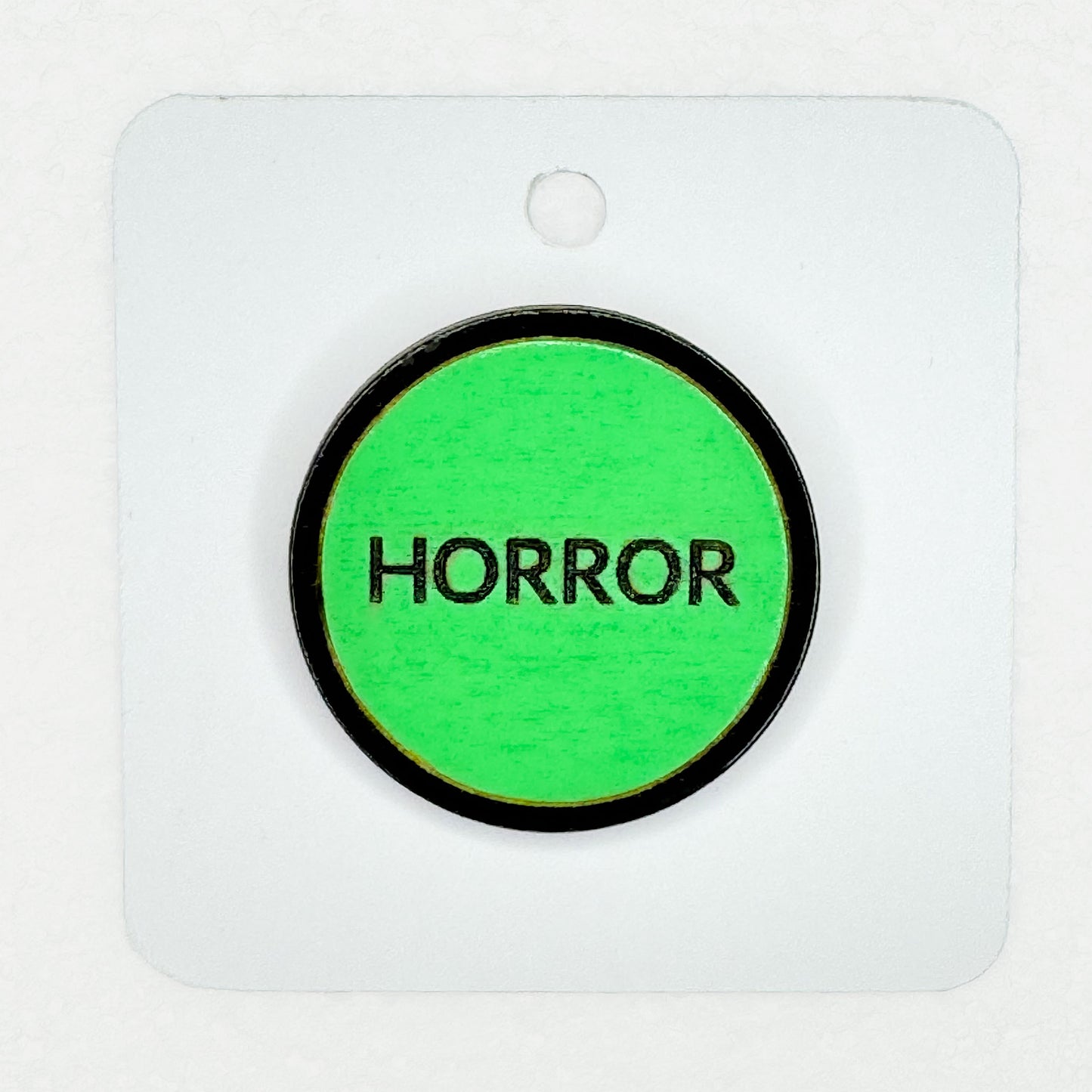 green retro-style vintage VHS horror label pin on white backing card with white background