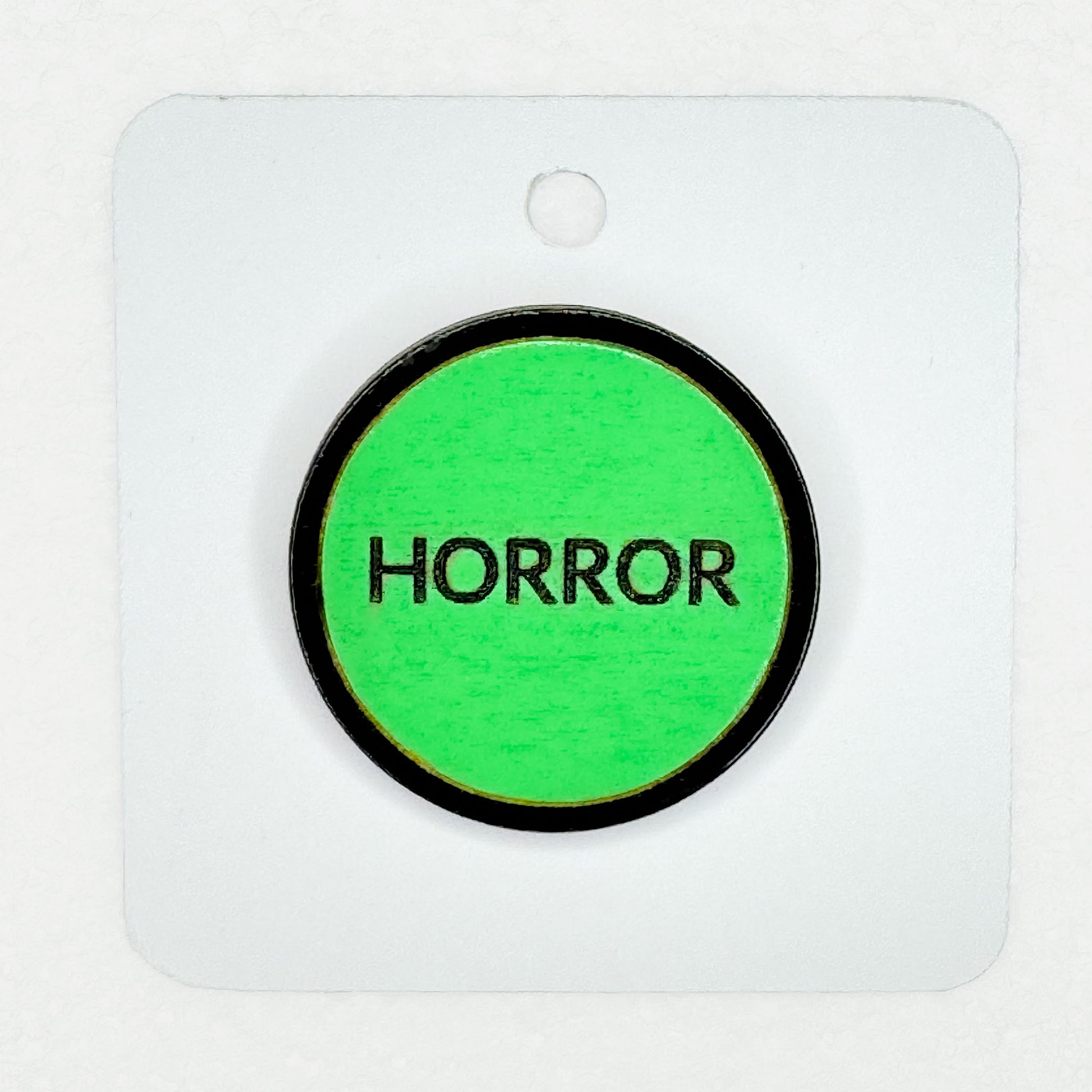 green retro-style vintage VHS horror label pin on white backing card with white background