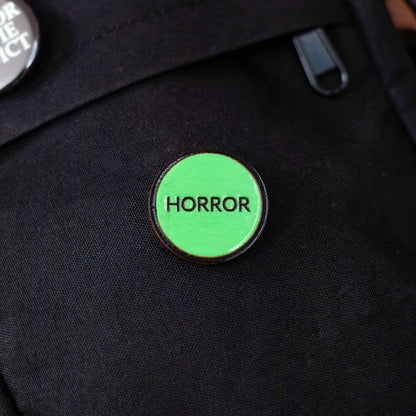 retro green VHS 'Horror' label pin on a black bag 