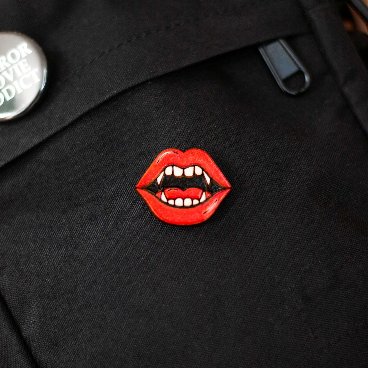 Black bag with a red lips and vampire fangs brooch on a dark background