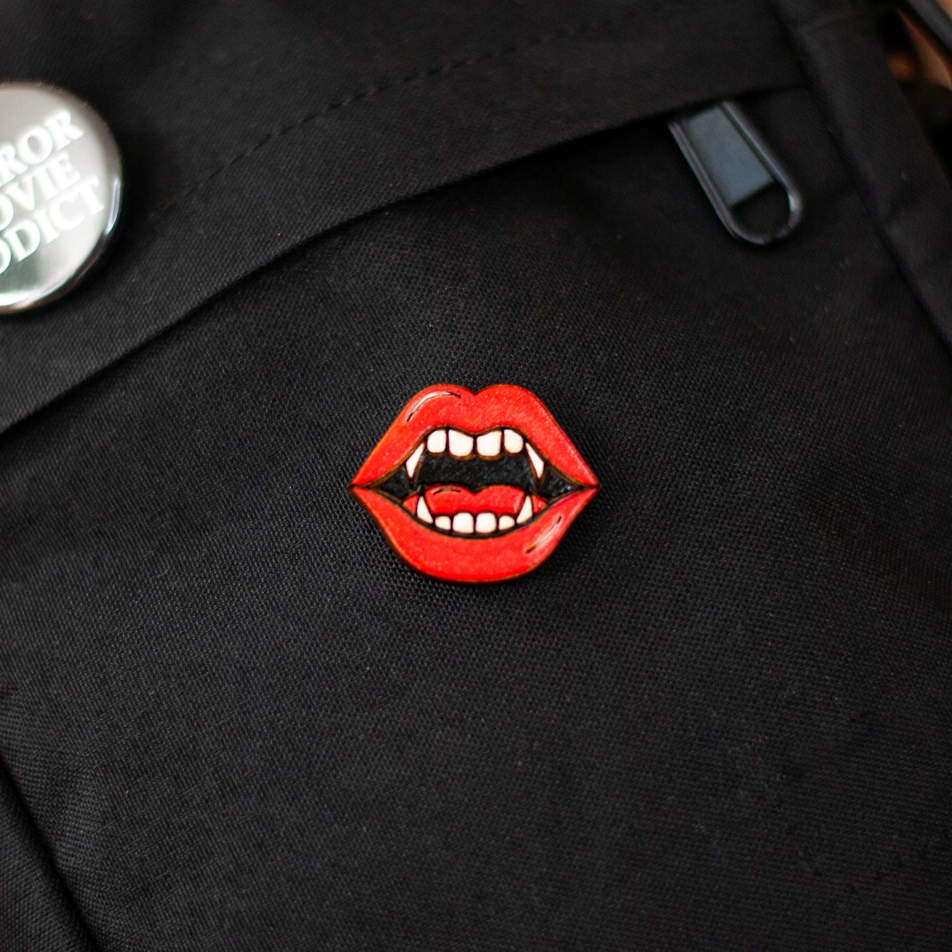 Black bag with a red lips and vampire fangs brooch on a dark background