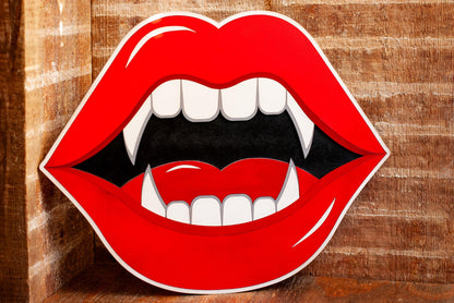 Wooden wall art of red lips with fangs on a wooden background
