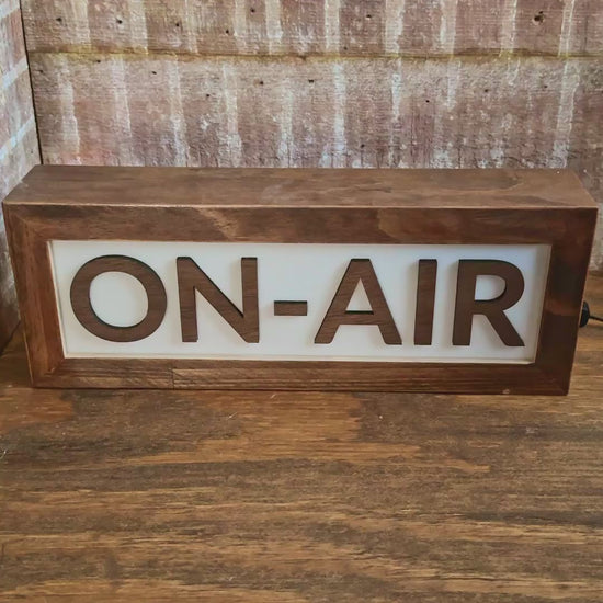 wooden On Air studio light up sign in brown color being lit with light switch on wood desk in studio