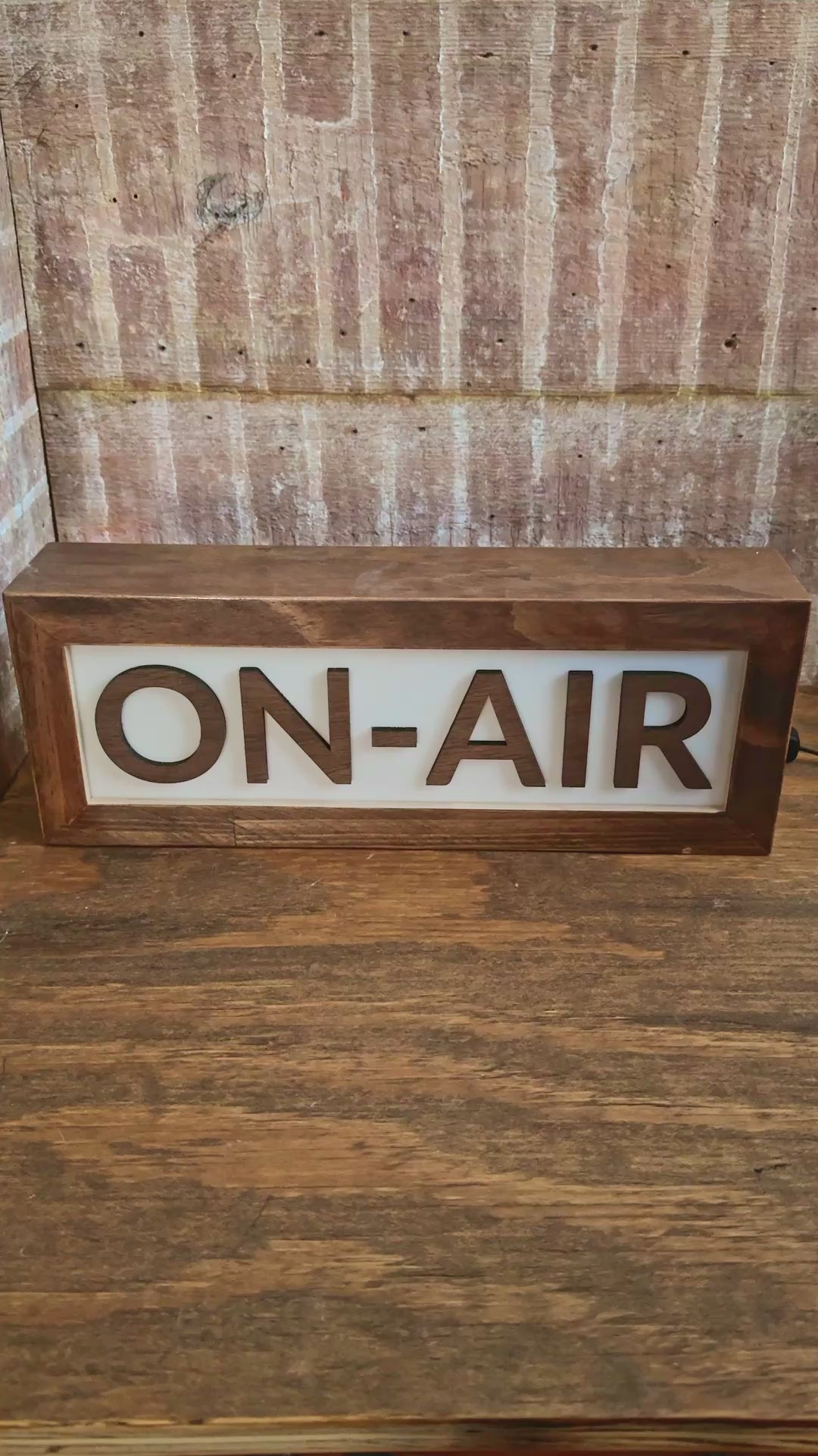 wooden On Air studio light up sign in brown color being lit with light switch on wood desk in studio